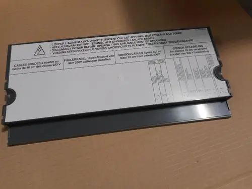 Blechabdeckung mit Anweisungen zur Kabelverlegung und Sicherheitsinformationen, gekennzeichnet mit dem Hersteller Remeha, für technische Anwendungen.